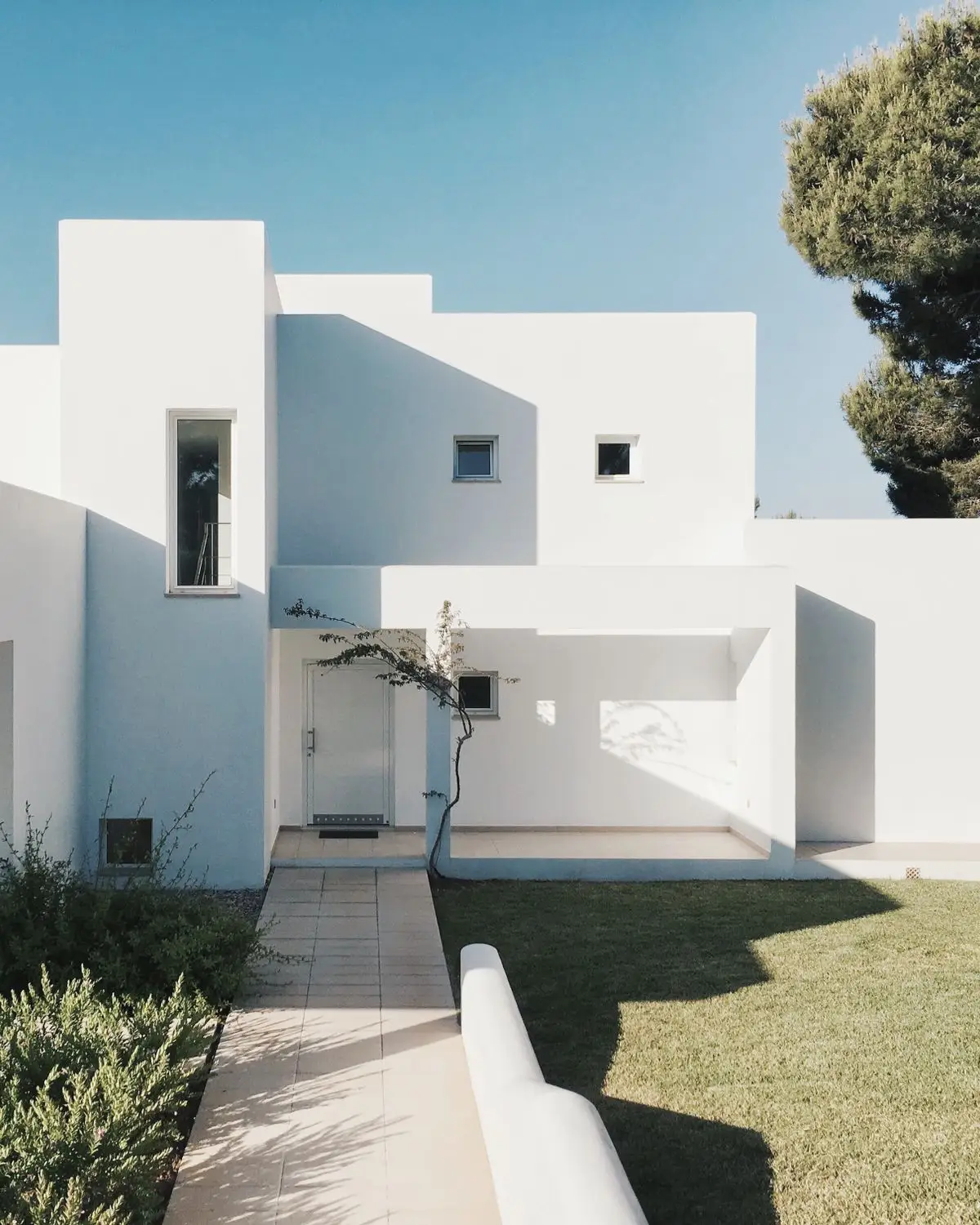 Vivienda unifamiliar de volúmenes blancos con jardín, proyectada por el estudio