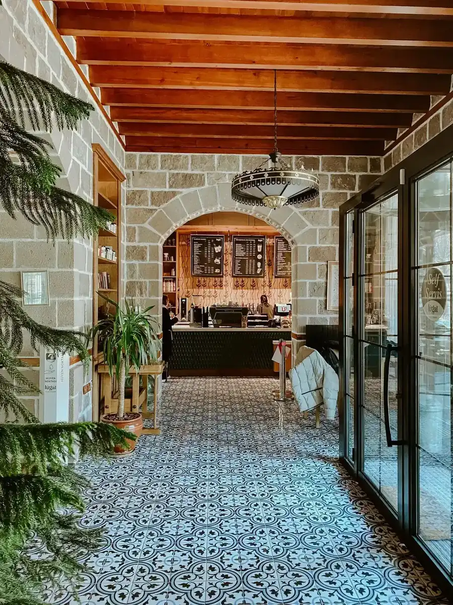 Interior de Café Aurora: arco de piedra, suelo hidráulico y luz cálida