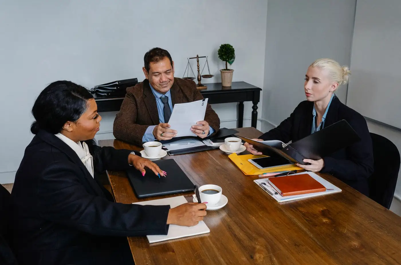Reunión de asesoramiento en el despacho: un gestor revisa la documentación con dos clientas
