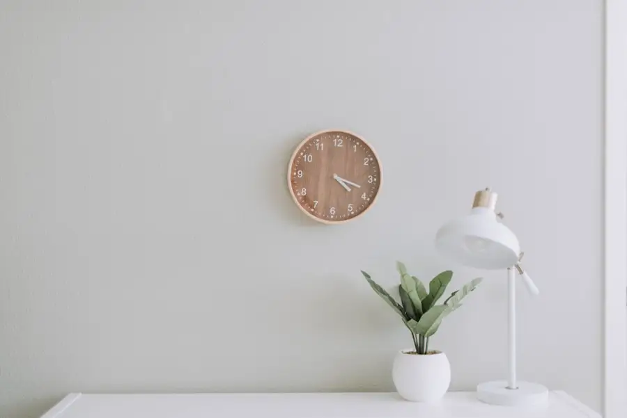 Reloj de madera en la pared sobre una mesa con una planta pequeña: el tiempo de una sesión de 50 minutos.